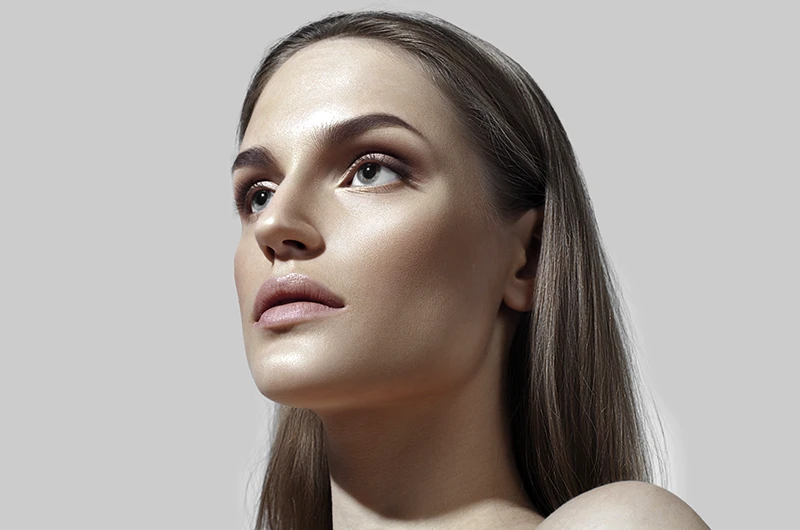 Retrato de perfil de mulher em fundo cinza, com luz realçando queixo e nariz