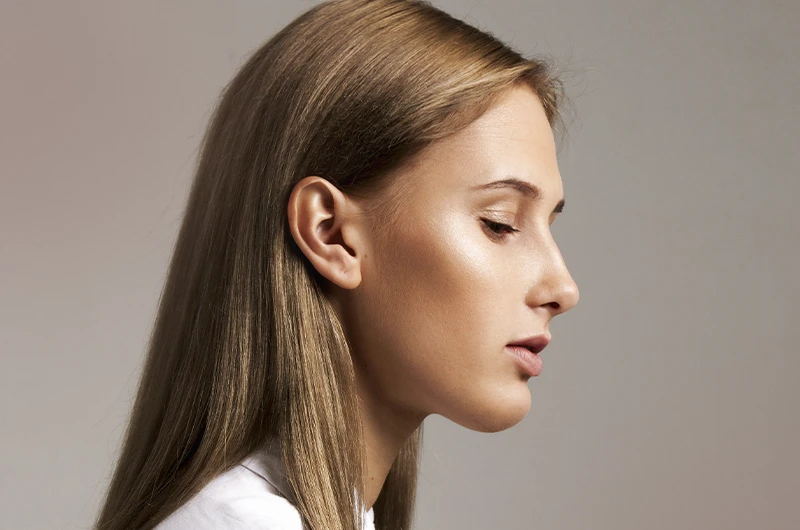 Mulher jovem fotografada de perfil em estúdio, com o queixo e a linha do nariz visíveis